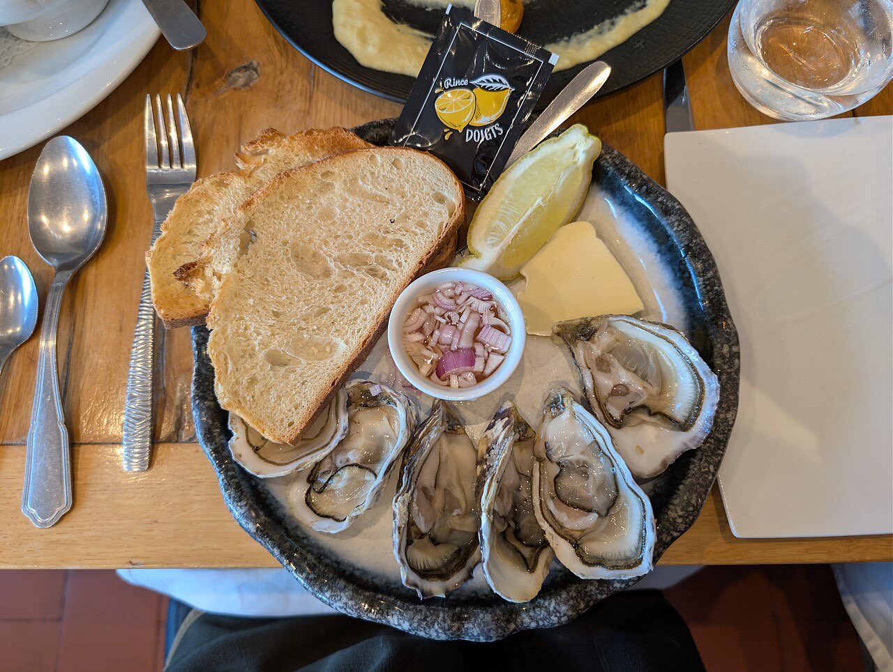 Une assiette de 6 huîtres ouvertes, avec du pain, du beurre, du citron et de l’échalote au vinaigre