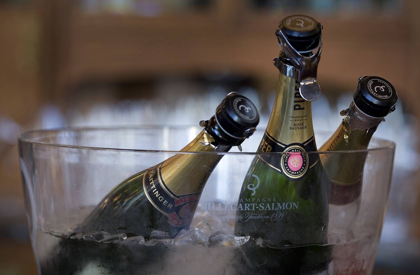 Deux bouteilles de Taittinger et un Piper-Heidsieck Rosé Sauvage, fermés par des bouchons hermétiques, dans un seau de glace transparent