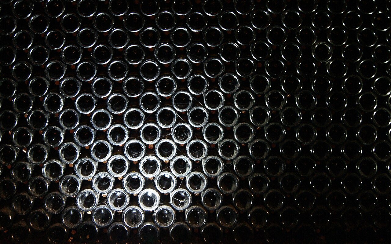 Empilement de centaines de bouteilles couchées dans une cave de vieillissement