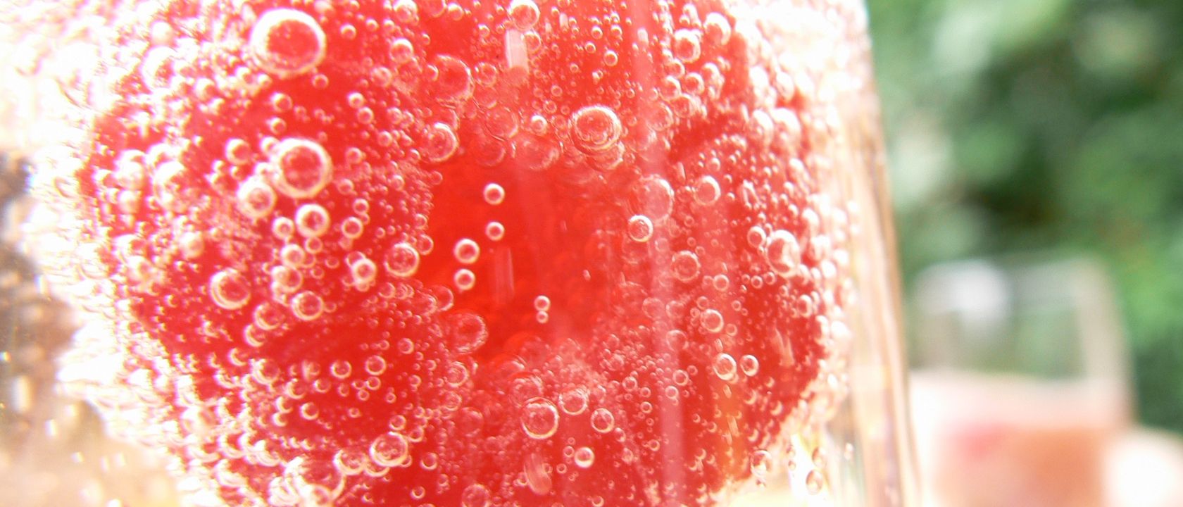 Framboise prise dans les bulles d’un cocktail au champagne, en gros plan