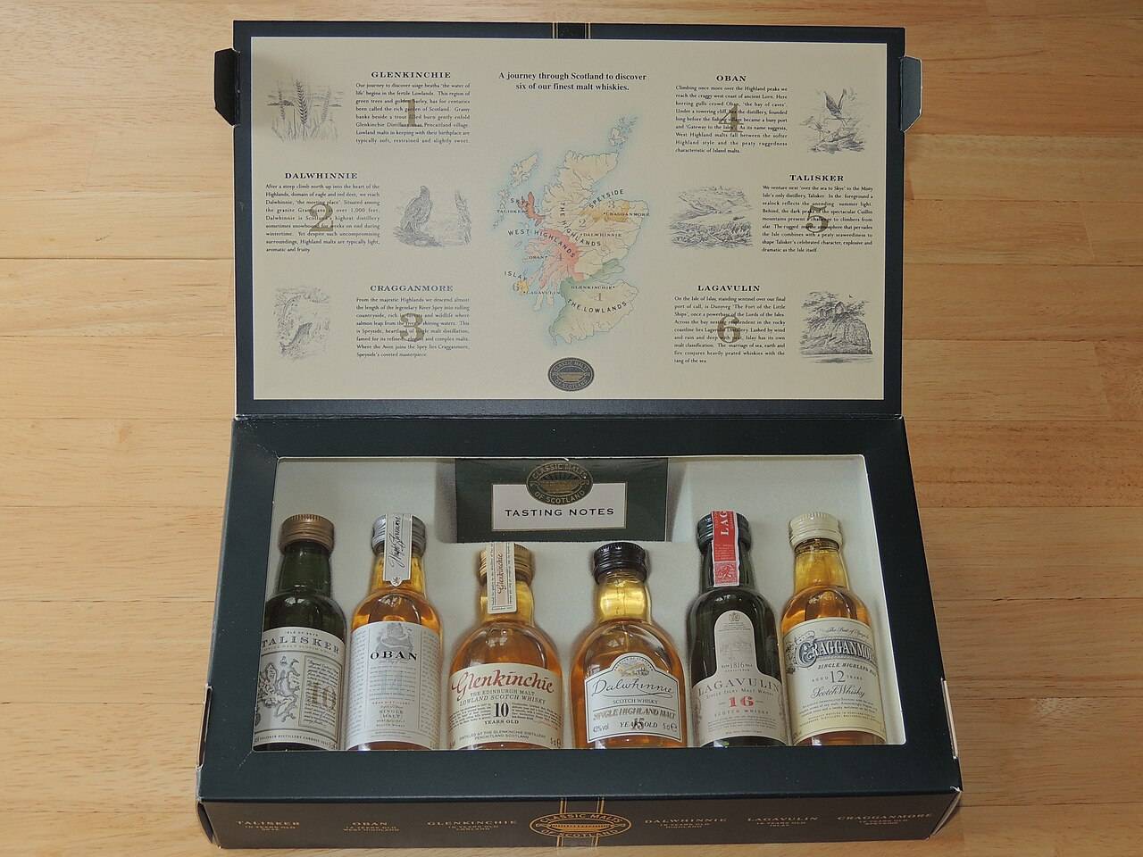 Un coffret ouvert de 6 miniatures de whisky écossais de 5 cl, avec une carte de l’Écosse et un livret de dégustation