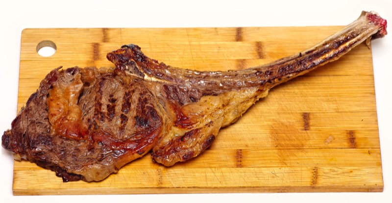 Une côte de bœuf grillée servie avec des frites et un verre de vin rouge