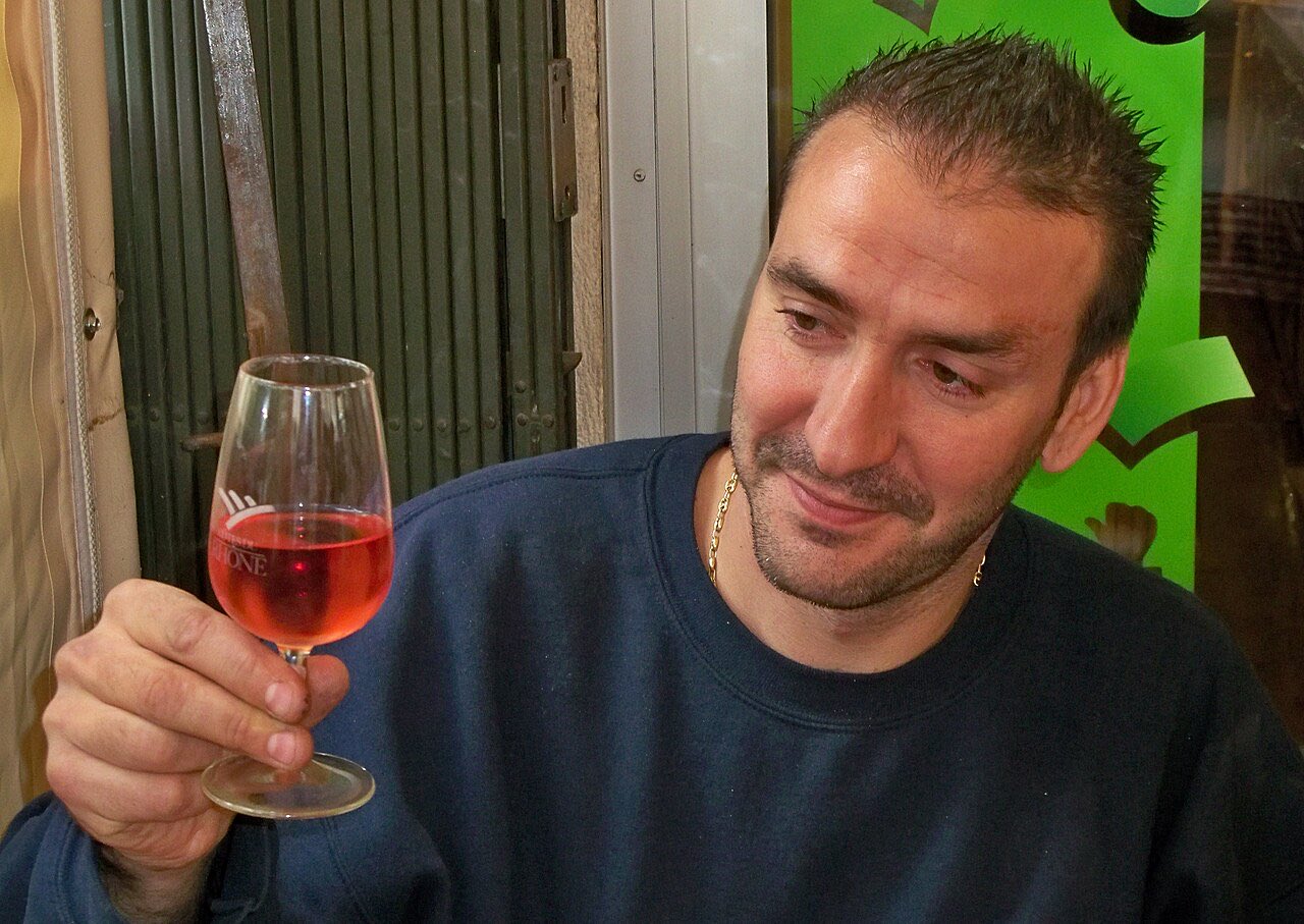 Un dégustateur tient un verre INAO de rosé par la jambe et en observe la couleur