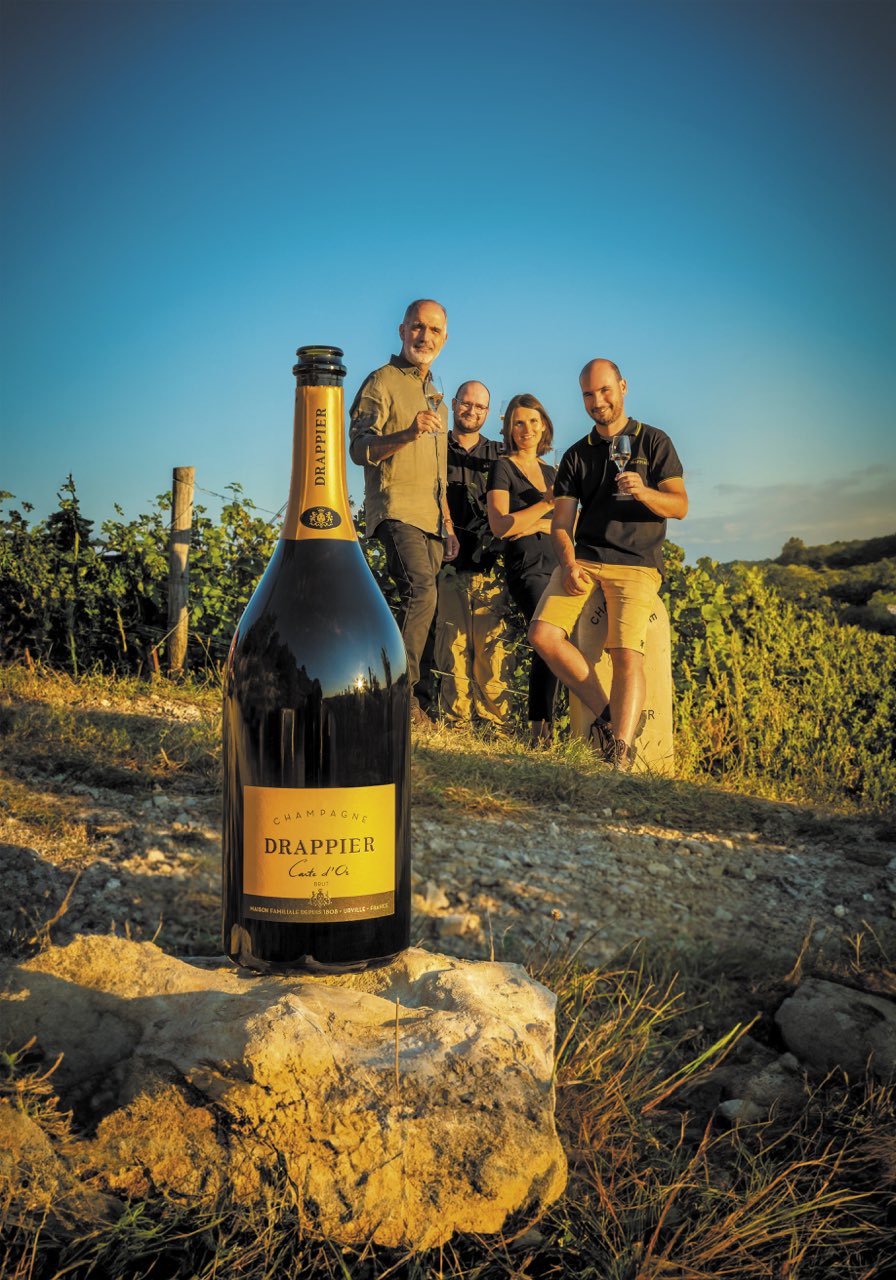 Michel, Antoine, Charline et Hugo Drappier dans les vignes, avec un grand format de Carte d’Or