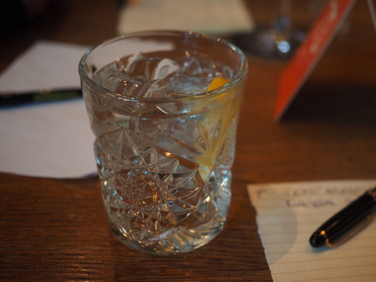 Un gin tonic servi dans un verre haut, sur une table en bois