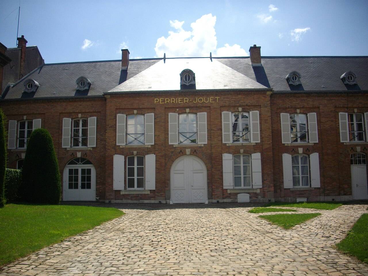 Un bâtiment de brique de la maison Perrier-Jouët, à son nom, au fond d’une cour pavée
