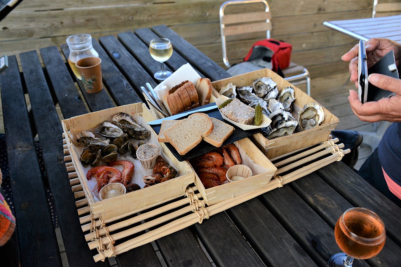 Des huîtres, des crevettes roses et des palourdes servies en cagettes sur une table en bois