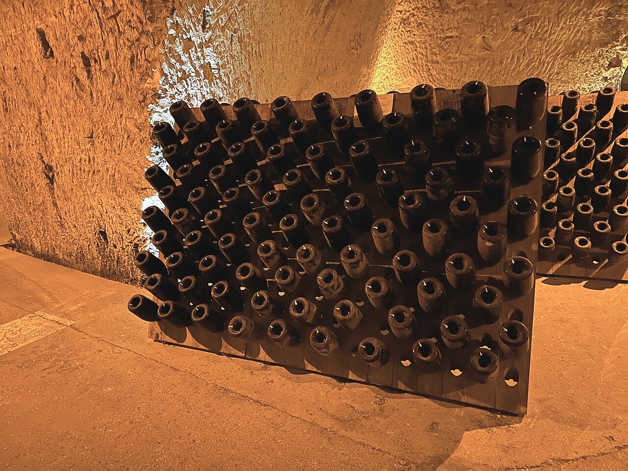 Pupitres de remuage garnis de bouteilles dans les caves crayeuses d’une maison de champagne