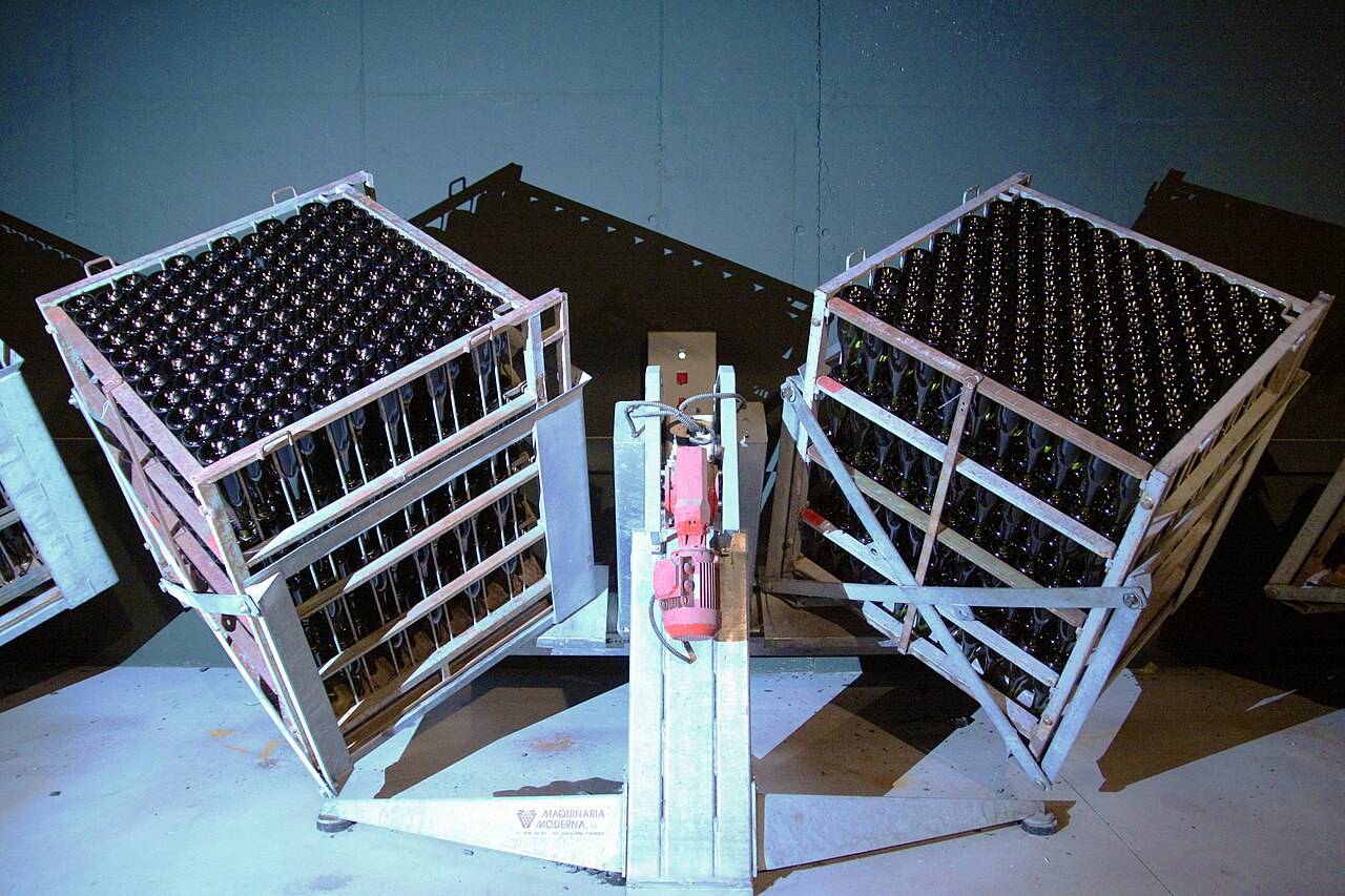 Un remueur automatique : deux caisses de bouteilles inclinées, de part et d’autre d’un moteur