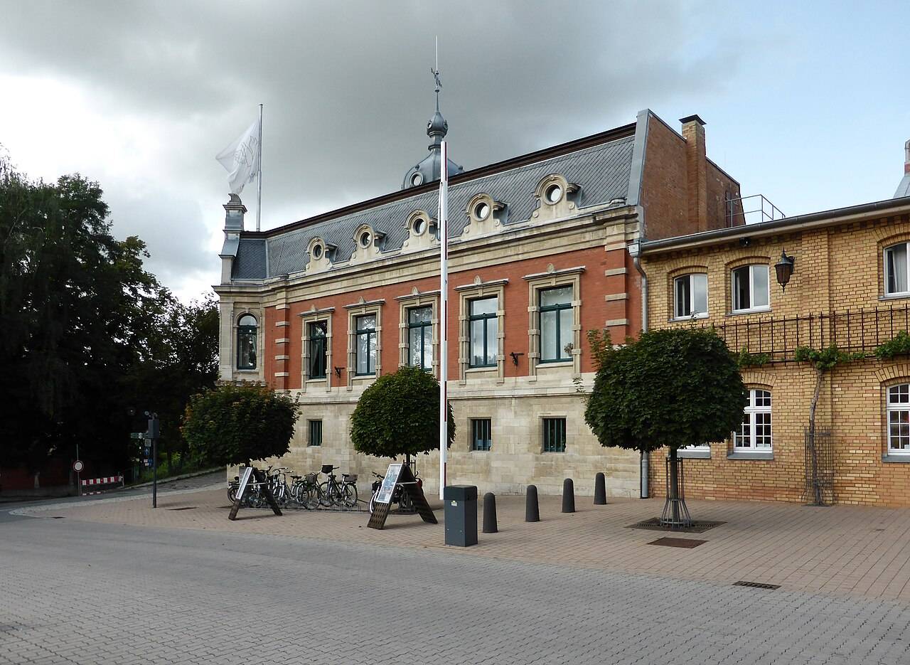 Le bâtiment de brique et de pierre à toit d’ardoise de la maison de sekt Rotkäppchen, à Freyburg, devant une place pavée