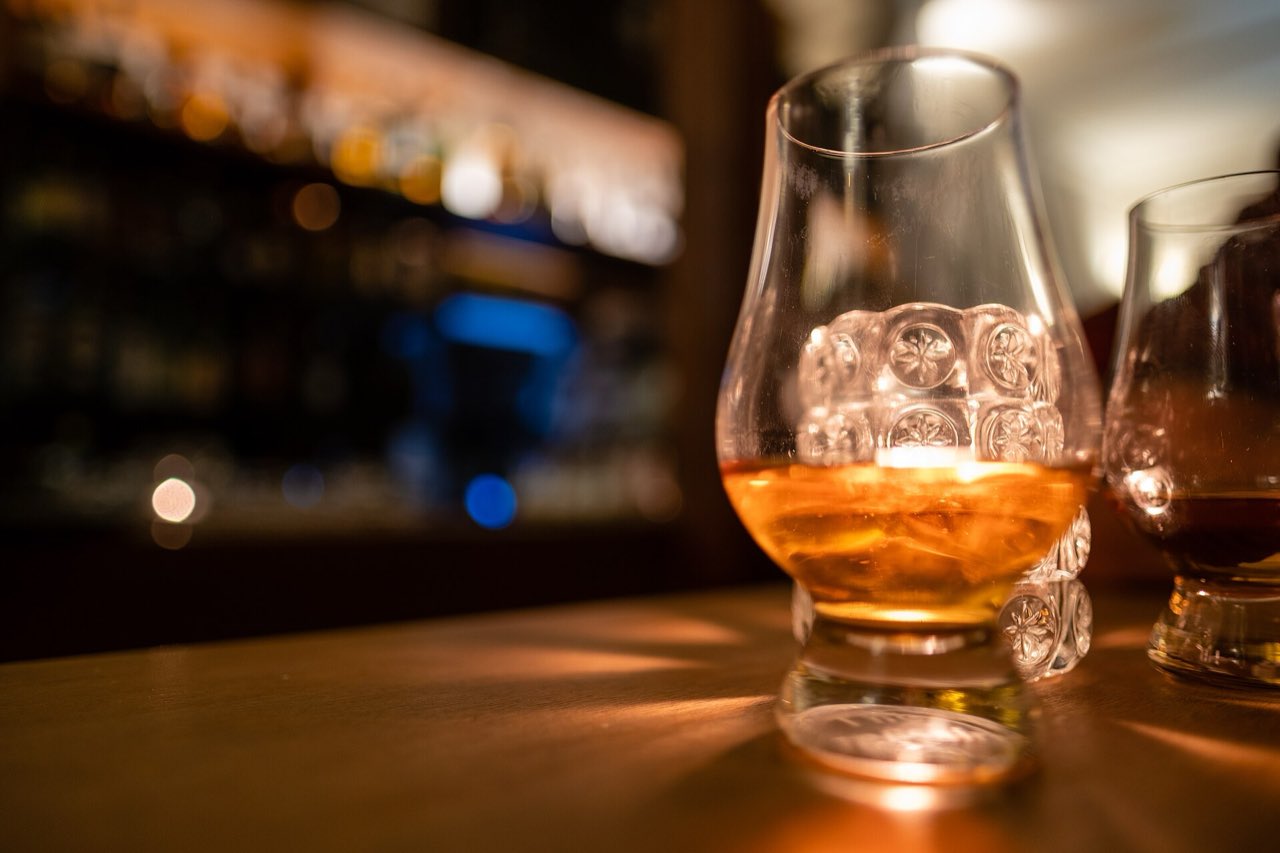Un verre de dégustation à whisky rempli de Lagavulin 16 ans, sur un comptoir de bar