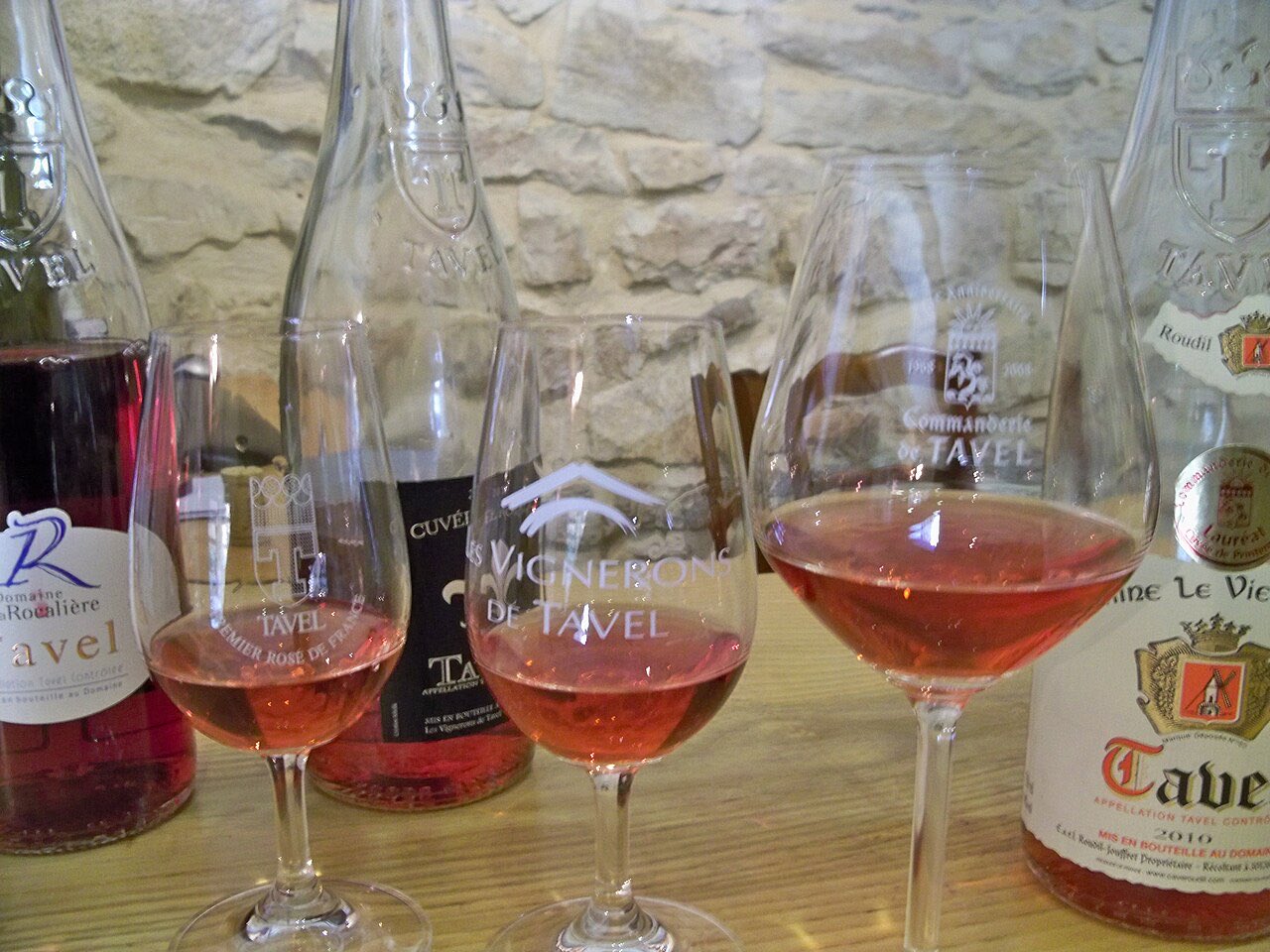 Du rosé de Tavel dans 2 verres INAO et un verre à vin plus grand, devant des bouteilles de Tavel