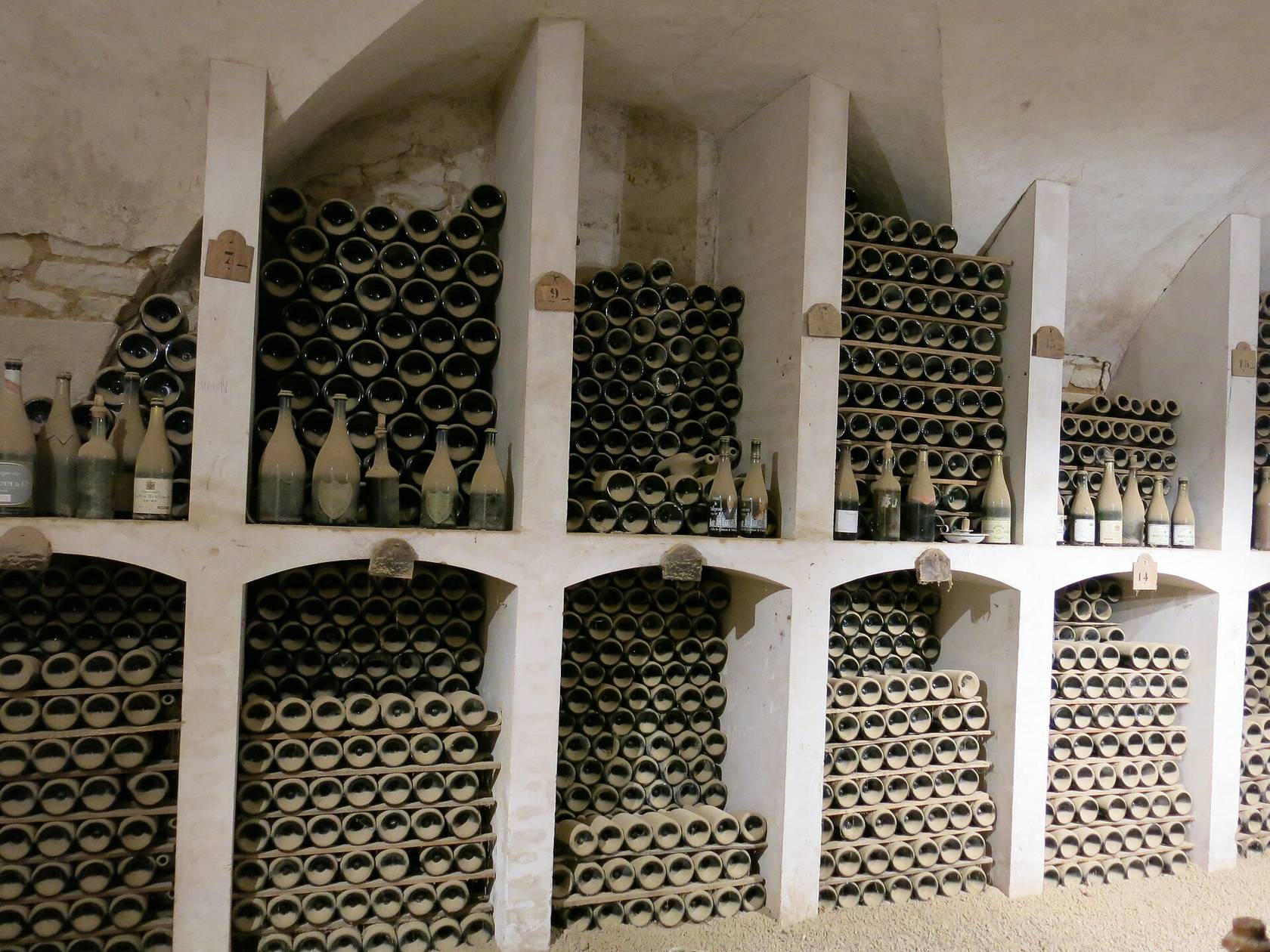 Des niches voûtées blanchies à la chaux, remplies de vieilles bouteilles couchées et couvertes de poussière, dans la cave du château de Valençay